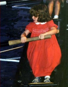 Young girl in a red dress learning how to row a boat